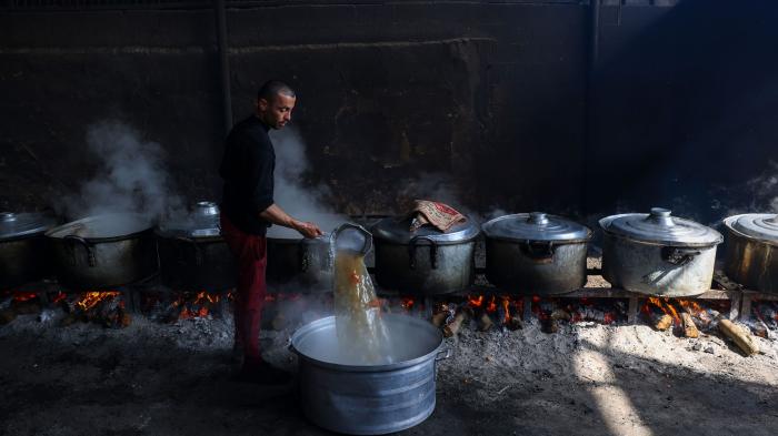 Palestinians prepare meals at a UN shelter to be distributed to displaced people in Rafah, in the southern Gaza Strip, October 23, 2023.