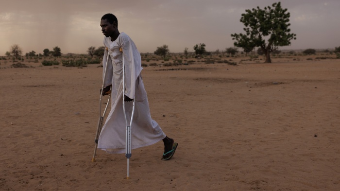 A man walks using crutches in a refugee camp